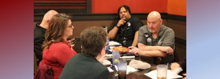 five people talking at a restaurant table