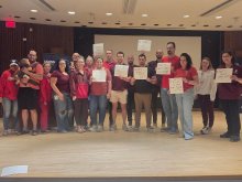 group portrait UHP nurses on Keller stage, some holding signs objecting to arbitrary removal of retention and recruitment stipends in critically understaffed areas